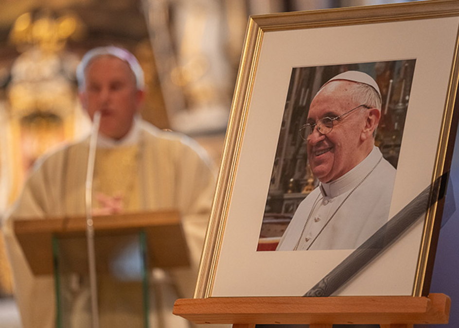 Foto von Franziskus auf einer Staffelei, im Hintergrund Weihbischof Theising