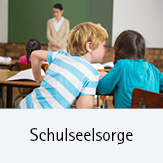 Schulseelsorge; Symbolbild: Zwei Schüler flüstern im Klassenraum